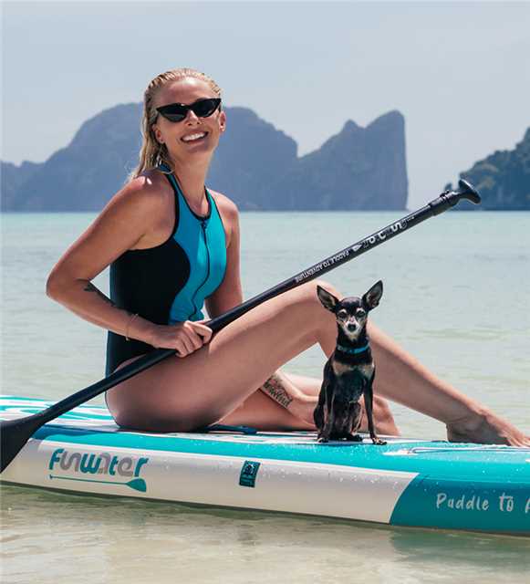A woman having a great time paddle boarding with her dog.