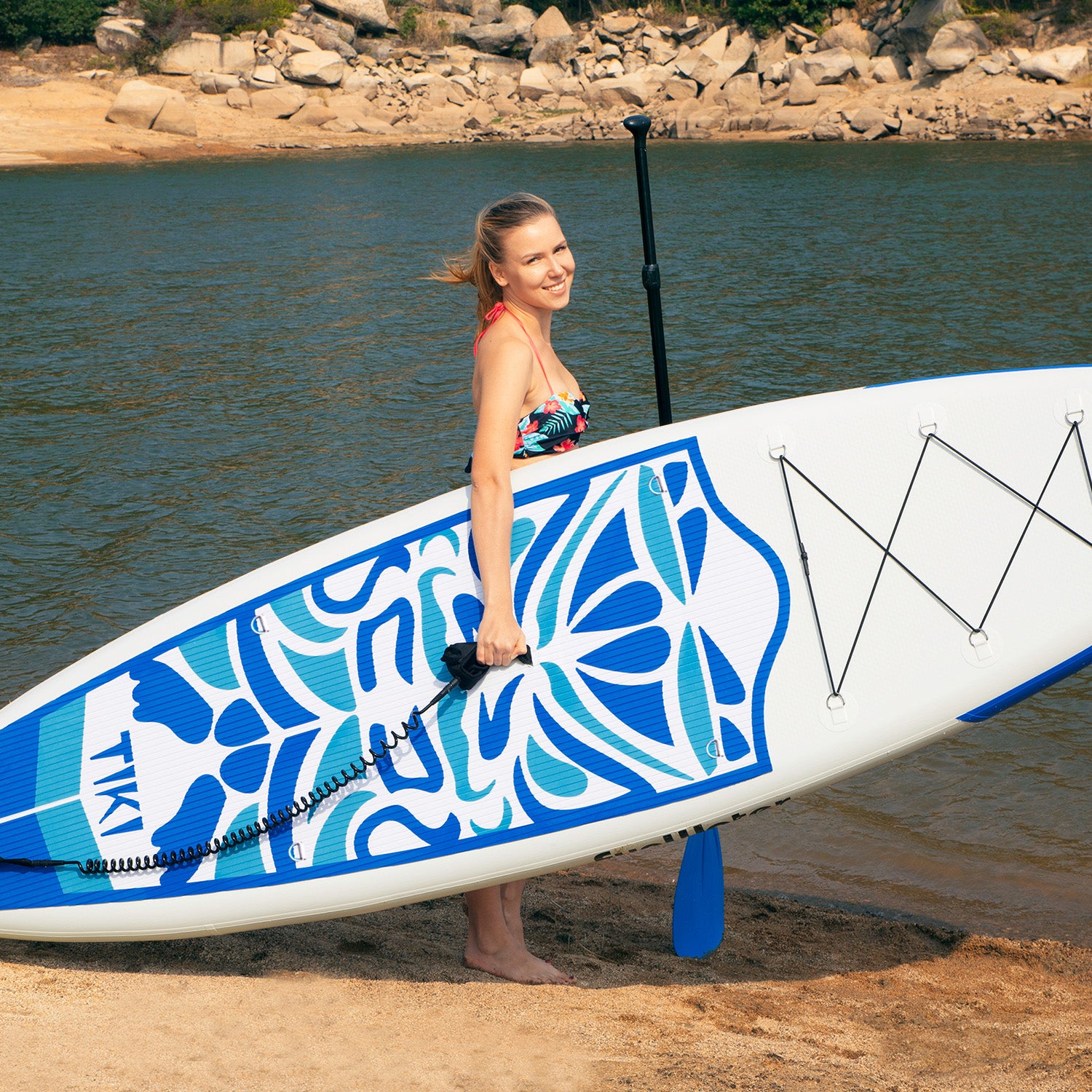 Funwater inflatable paddle board is held by a woman on the beach