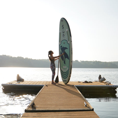 A woman with a paddleboard standing on the shore